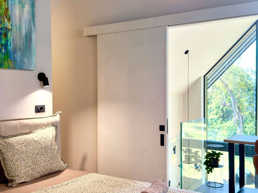 A bedroom with a big window onto the trees