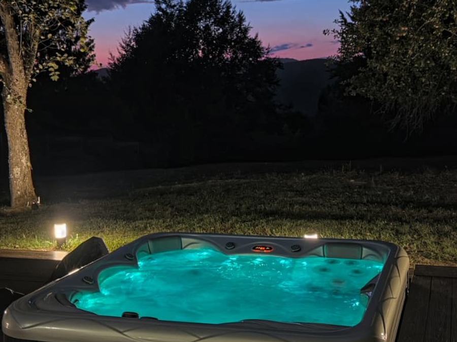 The lit hot tub on the deck at dusk