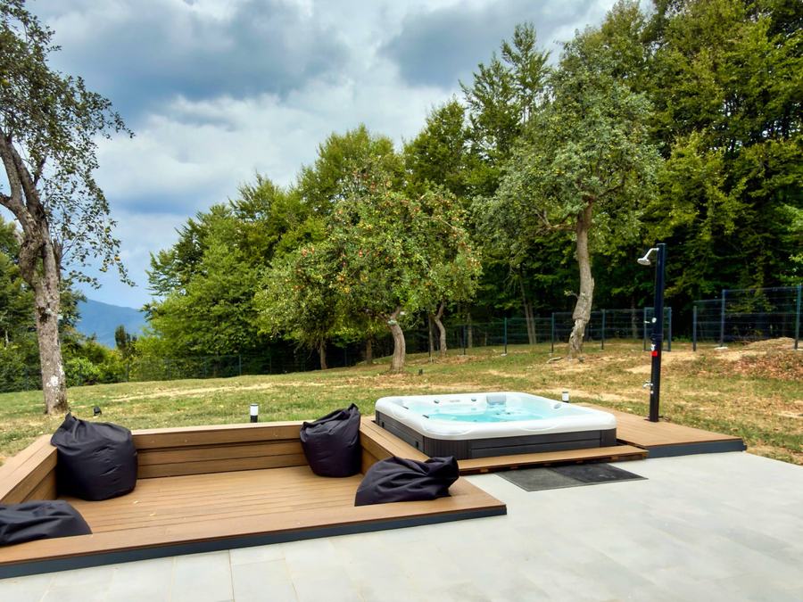 The wooden deck with the hot tub and the meadow