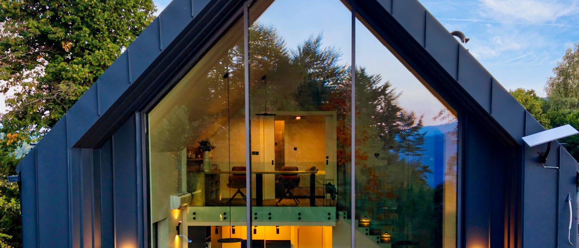 The glass front at dusk, the forest reflected in it